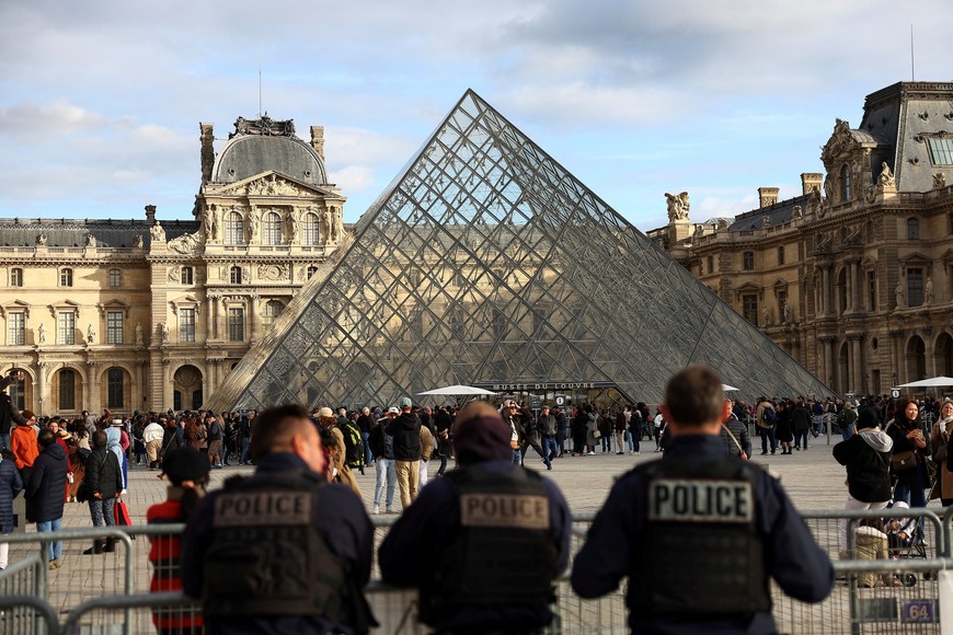 Police officers stand guard near the Louvre Pyramid, after French police arrested suspects in the Louvre heist case, at the Louvre Museum in Paris, France, October 26, 2025. REUTERS/Abdul Saboor