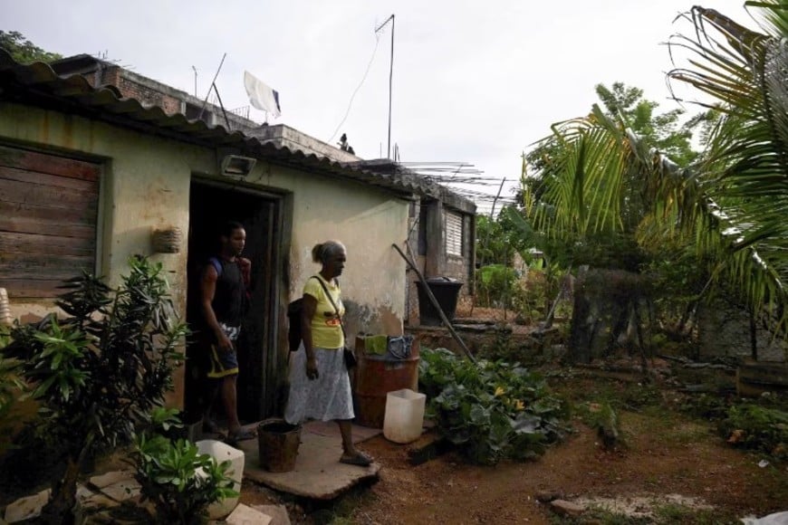 Mujeres salen de su casa para refugiarse temporalmente antes de la llegada del huracán Melissa a La Habana, Cuba.