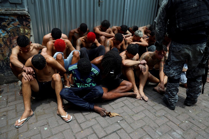 Suspected drug dealers sit on the ground after they were detained by members of the military police special unit, during a police operation against drug trafficking at the favela do Penha, in Rio de Janeiro, Brazil October 28, 2025. REUTERS/Aline Massuca