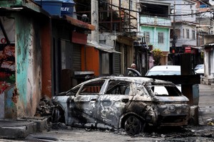 A person looks on behind a burnt car during a police operation against drug trafficking at the favela do Penha, in Rio de Janeiro, Brazil October 28, 2025. REUTERS/Aline Massuca