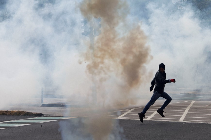 A protester runs as tear gas smoke fills the air, on the day of a peaceful march of resistance called by indigenous organisations and other social movements, in Quito, Ecuador, October 12, 2025. REUTERS/Karen Toro     TPX IMAGES OF THE DAY