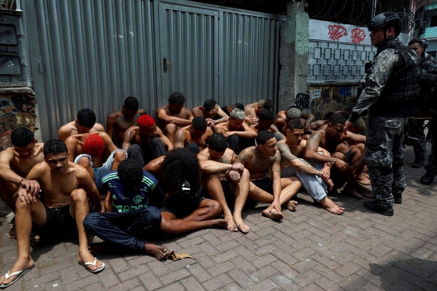 Suspected drug dealers sit on the ground after they were detained by members of the military police special unit, during a police operation against drug trafficking at the favela do Penha, in Rio de Janeiro, Brazil October 28, 2025. REUTERS/Aline Massuca