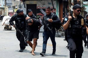 A man is detained by police officers during a police operation against drug trafficking at the favela do Penha, in Rio de Janeiro, Brazil October 28, 2025. REUTERS/Aline Massuca