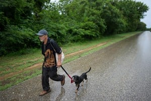 Un hombre y su perro corren hacia un refugio en Guamá, Cuba. Reuters