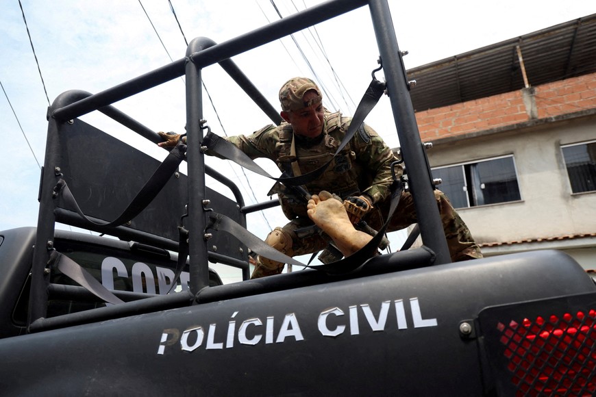 SENSITIVE MATERIAL. THIS IMAGE MAY OFFEND OR DISTURB    A member of the tactical police unit stands in the back of a vehicle while transporting a dead body during a police operation against drug trafficking at the favela do Penha, in Rio de Janeiro, Brazil, October 28, 2025. REUTERS/Aline Massuca TPX IMAGES OF THE DAY