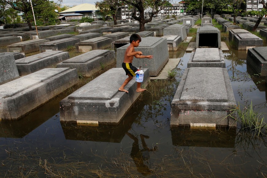 Residents stand on tombs ahead of the commemoration of All Saints Day, at a flooded cemetery in Macabebe, Pampanga, in northern Philippines, October 26, 2016. REUTERS/Erik De Castro filipinas pampanga filipinas celebracion del dia de los muertos cementerio de todos los santos