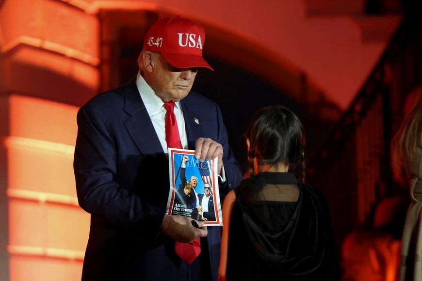 U.S. President Donald Trump displays a print of a TIME cover that mentions his 2024 assassination attempt, that a girl give him to sign, during a Halloween event for children at the White House in Washington, D.C., U.S., October 30, 2025. REUTERS/Kylie Cooper TPX IMAGES OF THE DAY