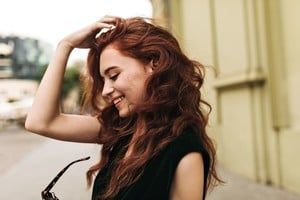 Curly woman putting off sunglasses and smiling