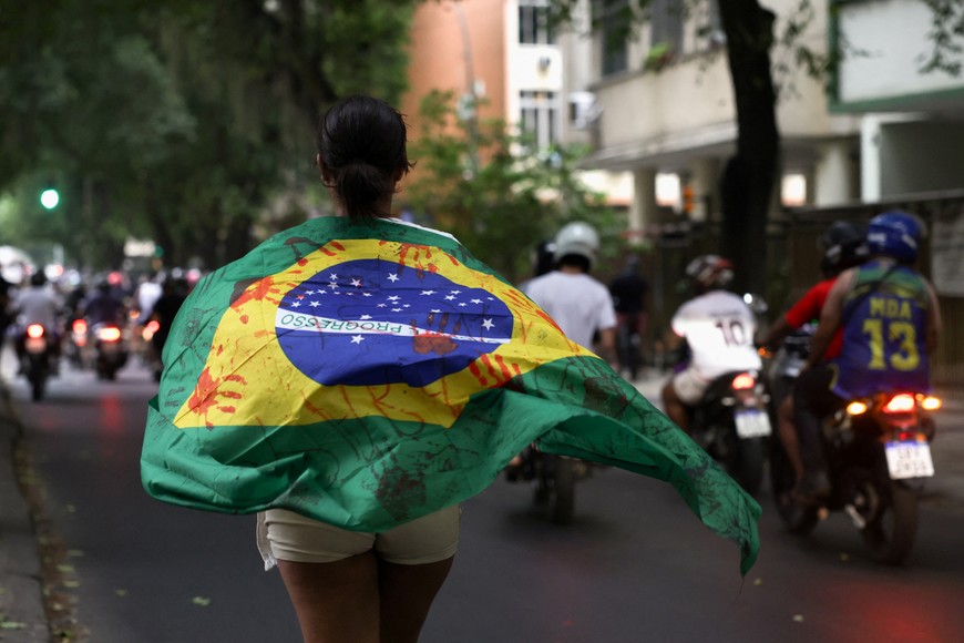 A woman draped in a Brazilian flag marked with fake blood stains protests, the day after a deadly police operation against drug trafficking at the favela do Penha, in Rio de Janeiro, Brazil October 29, 2025. REUTERS/Ricardo Moraes