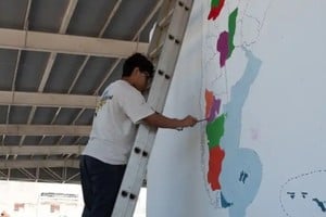 Montado a la escalera, un alumno del Industrial avanza en el coloreado de la provincia de Río Negro. Foto: Gentileza