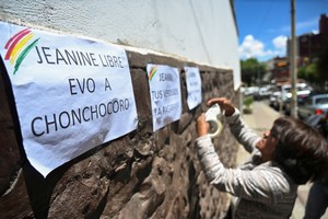 A woman pastes signs in support of Bolivia's former president Jeanine Anez on the prsion wall, as  Anez waits to be released from prison, after several years of preventive detention linked to legal proceedings stemming from her interim administration in 2019, in La Paz, Bolivia, November 5, 2025. REUTERS/Claudia Morales
