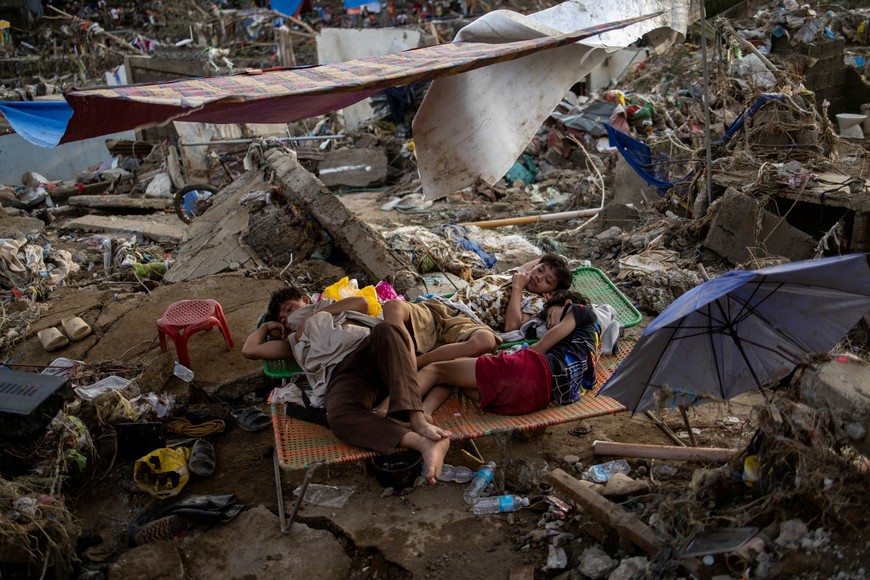 Residents rest on folding beds placed at the remains of their home after it was swept in the floods brought on by Typhoon Kalmaegi in Talisay, Cebu, Philippines, November 6, 2025. REUTERS/Eloisa Lopez