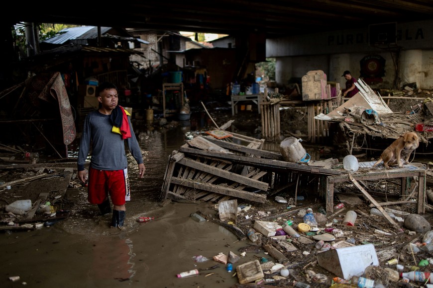 A man wades through muddy water in a community beneath Mananga Bridge following flooding caused by Typhoon Kalmaegi, in Talisay, Cebu, Philippines, November 6, 2025. REUTERS/Eloisa Lopez