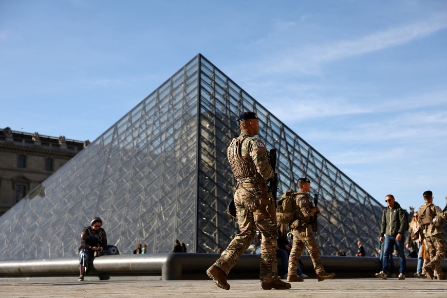 French soldiers from the "Sentinelle" security plan patrol past the glass Pyramid of the Louvre Museum as French police have arrested more suspects linked to the theft of treasures from the Louvre museum's Galerie d'Apollon (Apollo gallery), in Paris, France, October 30, 2025. REUTERS/Abdul Saboor