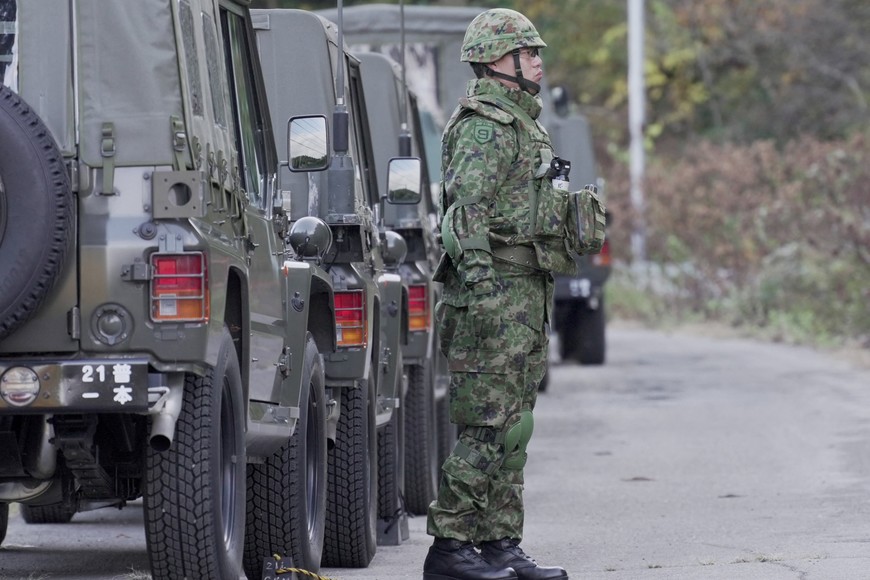 A member of Japan Self-Defense Forces (JSDF) stands next to military vehicles during a practice setting up a bear trap in Kazuno, Akita Prefecture, Japan, November 5, 2025. REUTERS/Tom Bateman