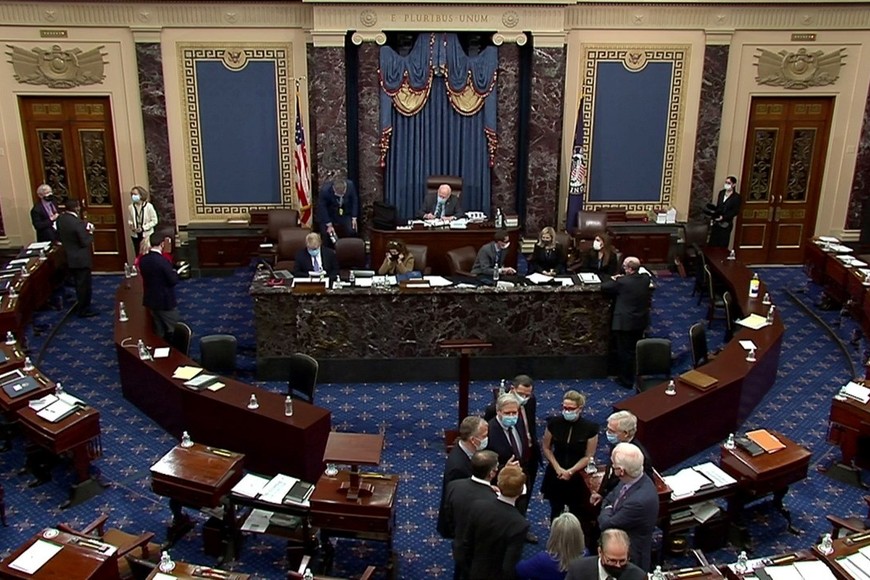 U.S. Senate Minority Leader Mitch McConnell (R-KY) huddles on the Senate floor with Senator Kyrsten Sinema (D-AZ), Senator John Barrasso (R-WY), Senator John Hoeven (R-ND), Senator Dan Sullivan (R-AK), Senator James Lankford (R-OK), Senator Joni Ernst (R-IA) and Senator John Cornyn (R-TX) and others after the Senate voted for witnesses during the fifth day of the impeachment trial of former president Donald Trump on charges of inciting the deadly attack on the U.S. Capitol, on Capitol Hill in Washington, U.S., February 13, 2021.  U.S. Senate TV/Handout via Reuters EDITORIAL USE ONLY NO COMMERCIAL SALES