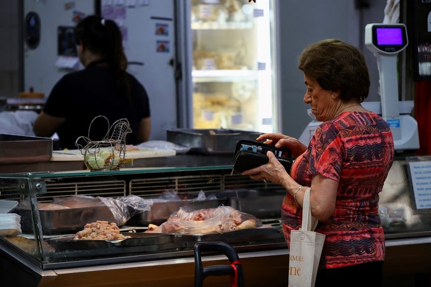 A costumer looks in her wallet to pay at a butcher shop in a local market, as Argentines ate more poultry per capita than beef in 2024, official data show that consumption of the red meat slid amid high inflation and tough austerity under libertarian President Javier Milei, in Buenos Aires, Argentina January 23, 2025. REUTERS/Agustin Marcarian