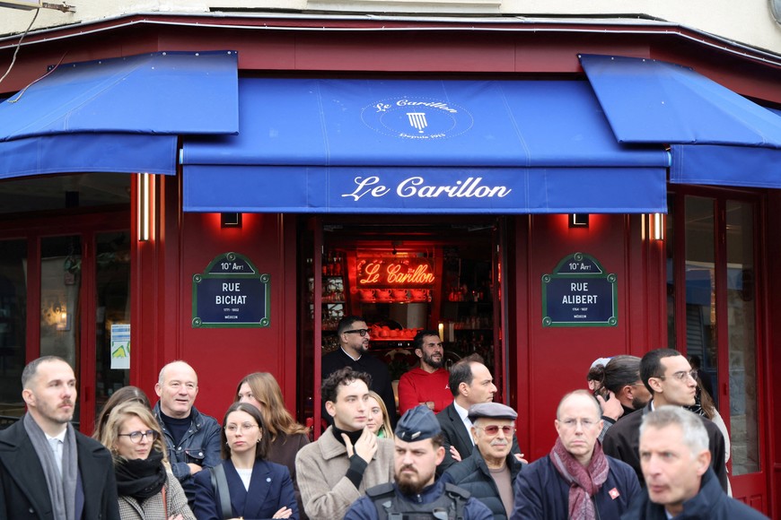 People gather prior to a ceromeny to pay tribute to victims at the intersection of of Bichat and Alibert streets near "Le Petit Cambodge" and "Le Carillon" in Paris on November 13, 2025, during ceremonies across Paris marking a decade since the terror attacks of November 13, 2015 in which 130 civilians were killed.     LUDOVIC MARIN/Pool via REUTERS