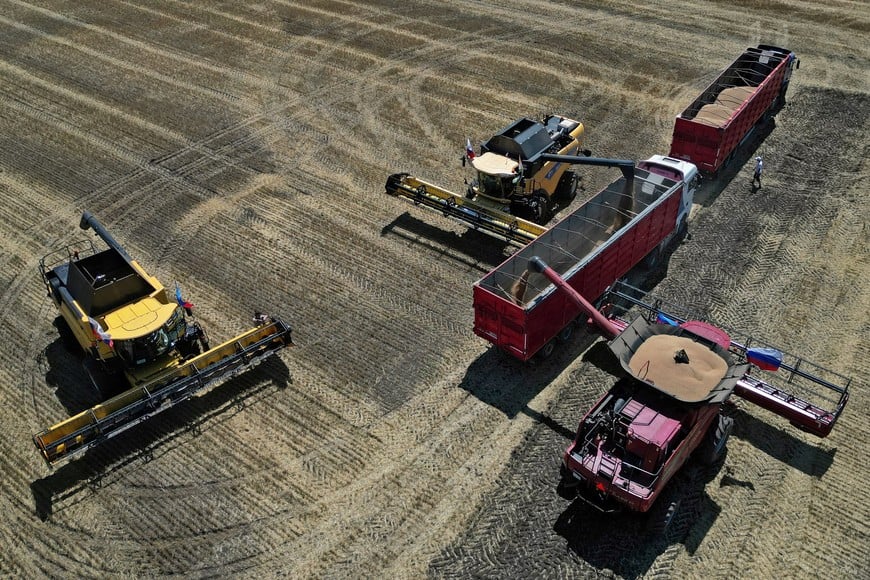 A drone view shows combines loading trucks with wheat during the start of the harvesting campaign in a field near the town of Starobilsk (Starobelsk) in the Luhansk Region, a Russian-controlled area of Ukraine, July 9, 2025. REUTERS/Alexander Ermochenko