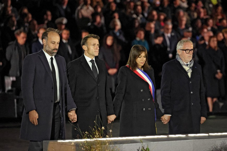 President of the Life for Paris victims association Arthur Denouveaux, France's President Emmanuel Macron, Paris' mayor Anne Hidalgo and President of the association "13Onze15 Fraternite-Verite" Philippe Duperron hold their hands during a ceremony marking a decade since the attacks of November 13, 2015 in which 130 civilians were killed, at the "Jardin du 13 novembre 2015" in Paris on November 13, 2025.     LUDOVIC MARIN/Pool via REUTERS
