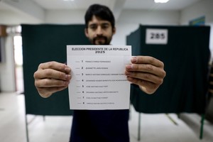 Un centro de votación en Santiago, donde uno de los votantes muestra la lista de candidatos en la boleta. Crédito: REUTERS/Juan Gonzalez