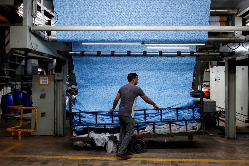 A worker inspects and arranges printed fabric sheets, at the printing unit of the textiles manufacturer of the Liberty Mills Limited, in Karachi, Pakistan August 2, 2025. REUTERS/Akhtar Soomro      TPX IMAGES OF THE DAY