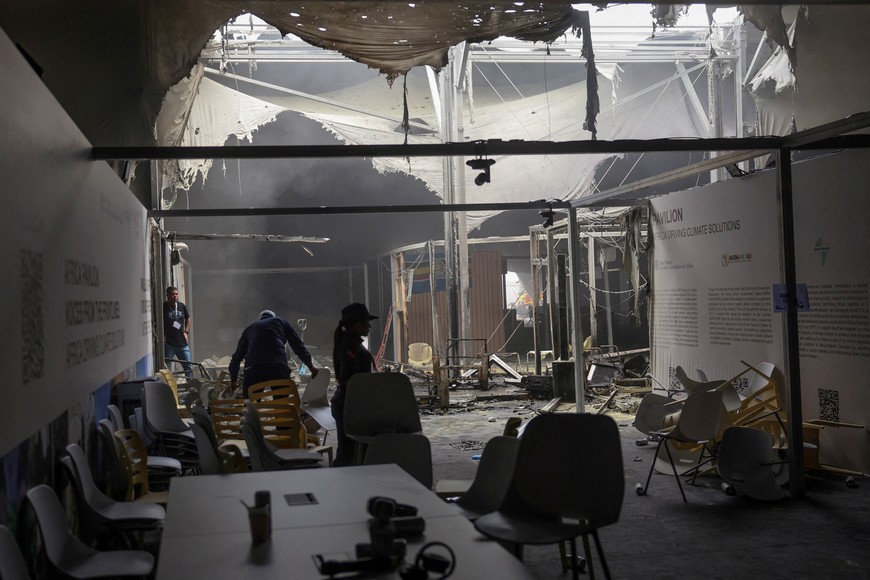 A person picks up chairs inside a damaged pavillion following a fire alert during the UN Climate Change Conference (COP30), in Belem, Brazil, November 20, 2025. REUTERS/Adriano Machado