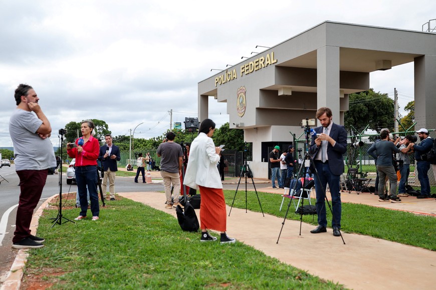 Members of the media work outside of Brazilian Federal Police Regional Headquarters, where Brazil's former President Jair Bolsonaro was taken after being placed in federal police custody as a preventative measure related to his house arrest, in Brasilia, Brazil, November 22, 2025. REUTERS/Mateus Bonomi