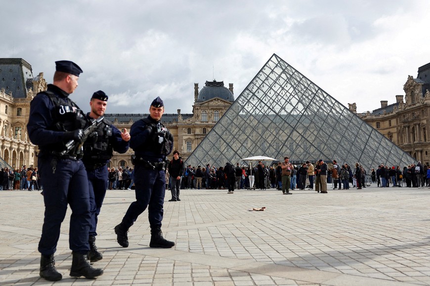 FILE PHOTO: French CRS riot police officers walk near the glass Pyramid of the Louvre Museum, after French police arrested suspects in the Louvre heist case, in Paris, France October 27, 2025. REUTERS/Abdul Saboor/File Photo
