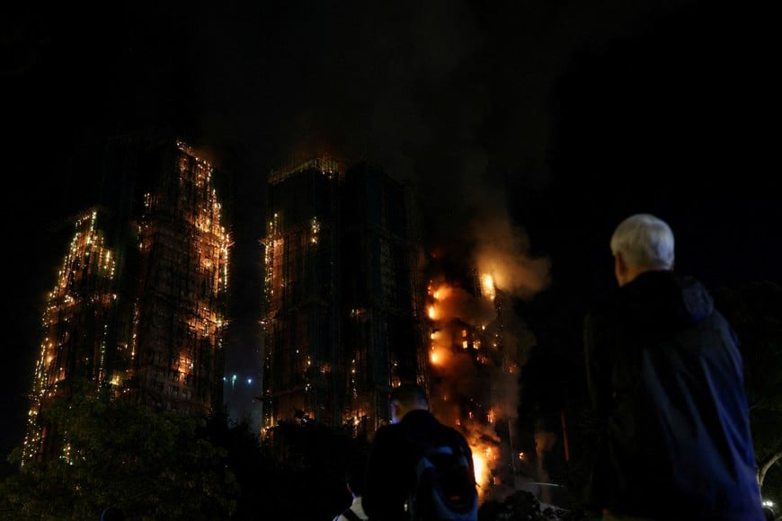 People watch as flames burn bamboo scaffolding across multiple buildings at Wang Fuk Court housing estate, in Tai Po, Hong Kong, China, November 26, 2025. REUTERS/Tyrone Siu     TPX IMAGES OF THE DAY