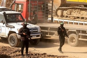 Miembros de Hamás escoltan un vehículo de la Cruz Roja hasta la "línea amarilla" detrás de la cual el Ejército de Israel se retiró bajo el alto el fuego.