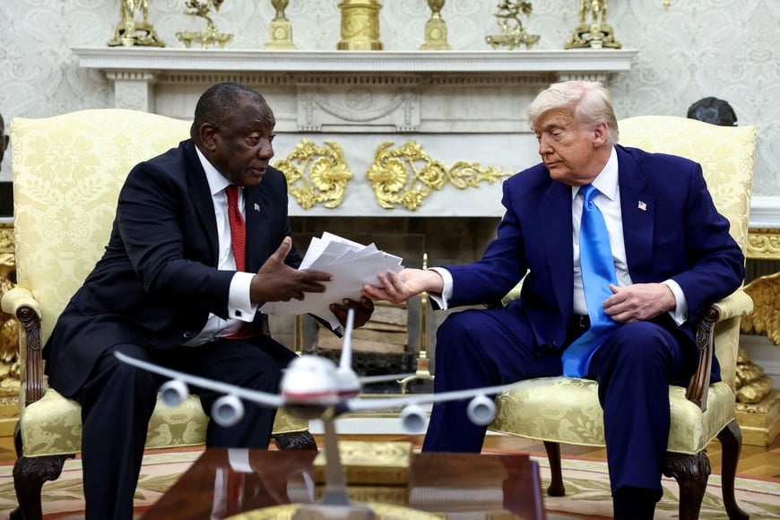U.S. President Donald Trump hands over to South African President Cyril Ramaphosa copies of articles that he said showed white South Africans who had been killed, in the Oval Office of the White House in Washington, D.C., U.S., May 21, 2025. REUTERS/Kevin Lamarque TPX IMAGES OF THE DAY