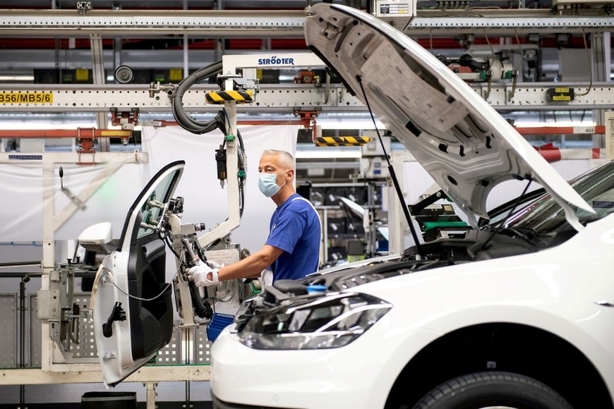 FILE PHOTO: A worker wears a protective mask at the Volkswagen assembly line after VW re-starts Europe's largest car factory after coronavirus shutdown in Wolfsburg, Germany, April 27, 2020, as the spread of the coronavirus disease (COVID-19) continues.    Swen Pfoertner/Pool via REUTERS/File Photo