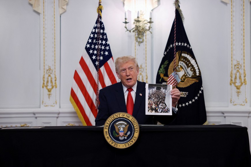 U.S. President Donald Trump holds the picture of what he says is a a refugee plane from Afghanistan as he participates in a call with service members of U.S. Army, JTF-Southern Border, 101st Airborne Division (Fort Huachuca, AZ), U.S. Marine Corps, Battalion Landing Team 3d Battalion 6th Marines (Puerto Rico), U.S. Navy, IWO JIMA ARG, 22 MEU, (Underway, SOUTHCOM AOR), U.S. Air Force, 7th Bomb Wing (Dyess AFB, Abilene, TX), U.S. Space Force, 18th Space Defense Squadron (Vandenberg Space Force Base, CA), and U.S. Coast Guard, USCGC FORREST REDNOUR, WPC-1129 (Underway), on Thanksgiving, in Palm Beach, Florida, U.S., November 27, 2025. REUTERS/Anna Rose Layden