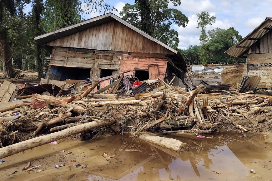 Tree trunks and debris lie in front of a damaged house in an area hit by deadly flash floods following heavy rains in Batang Toru, South Tapanuli, North Sumatra, Indonesia, November 29, 2025. REUTERS/Arif Nasution