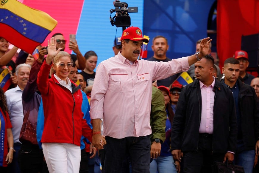 Venezuela's President Nicolas Maduro waves while holding the hand of his wife Cilia Flores during a ceremony to swear in new community-based organisations, as U.S. President Donald Trump’s administration ramps up pressure on Maduro’s government, in Caracas, Venezuela, December 1, 2025. REUTERS/Leonardo Fernandez Viloria
