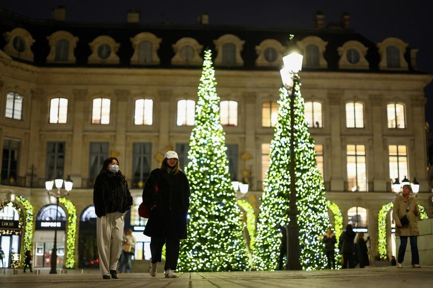 People walk near Christmas trees in Place Vendome as Paris marks the start of its Christmas holiday lights season, France, December 3, 2025. REUTERS/Gonzalo Fuentes