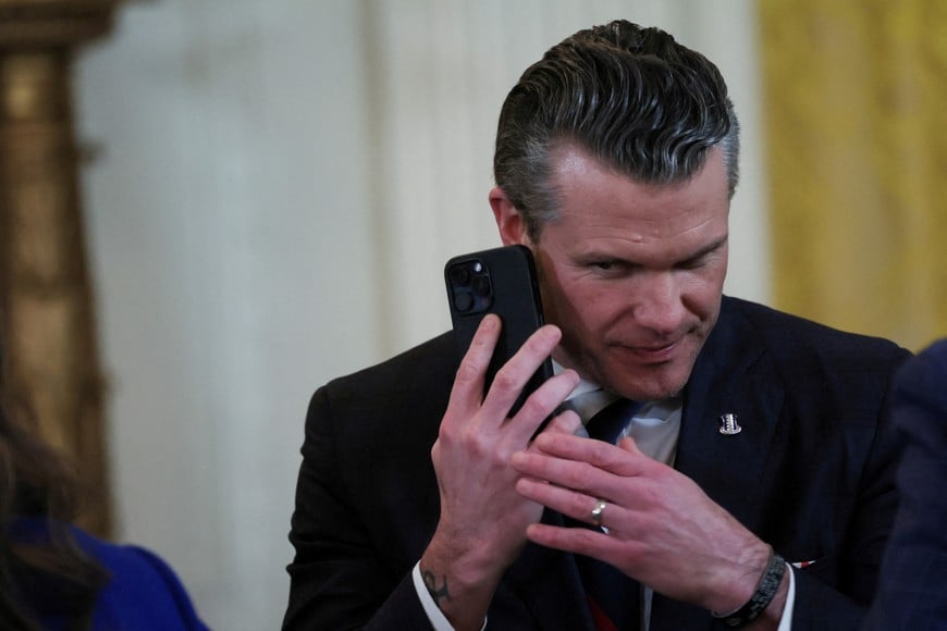 FILE PHOTO: U.S. Defense Secretary Pete Hegseth uses a phone as he attends a joint press conference of U.S. President Donald Trump and Israeli Prime Minister Benjamin Netanyahu in the East Room at the White House in Washington, U.S., February 4, 2025. REUTERS/Leah Millis/File Photo
