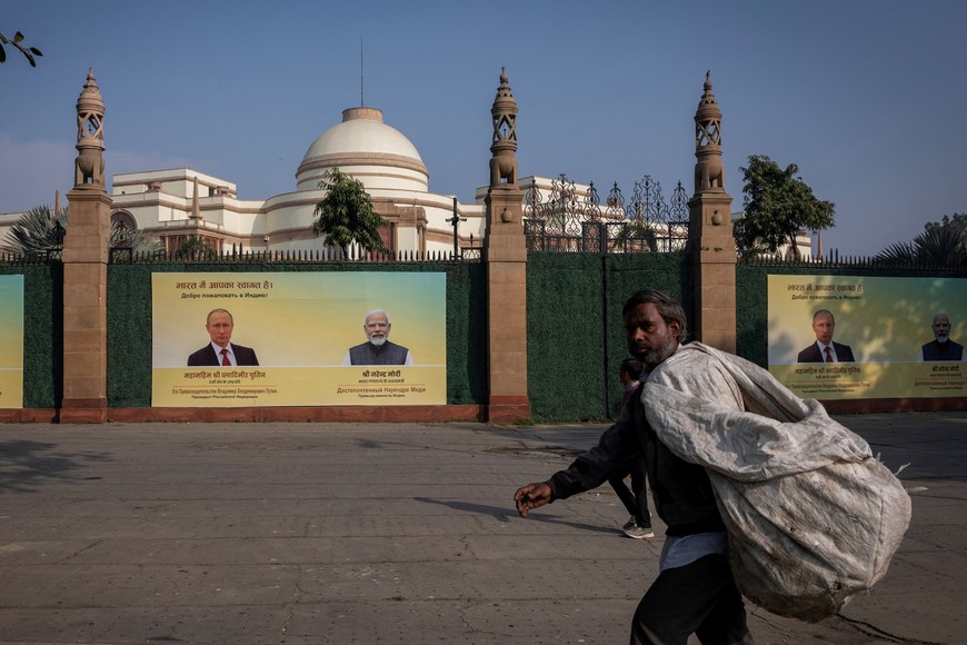A ragpicker walks past a hoarding with images of Russian President Vladimir Putin and Indian Prime Minister Narendra Modi ahead of Putin's visit, in New Delhi, India, December 4, 2025. REUTERS/Adnan Abidi
