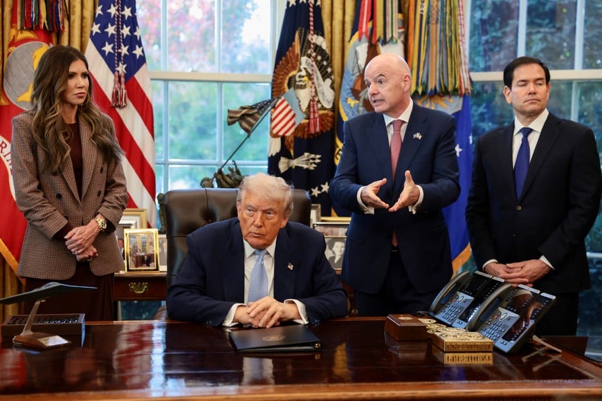 U.S. President Donald Trump sits while FIFA President Gianni Infantino, U.S. Secretary of State Marco Rubio, and U.S. Homeland Security Secretary Kristi Noem stand by his side, as he meets with the White House Task Force on the FIFA World Cup 2026 in the Oval Office at the White House in Washington, D.C., U.S., November 17, 2025. REUTERS/Evelyn Hockstein