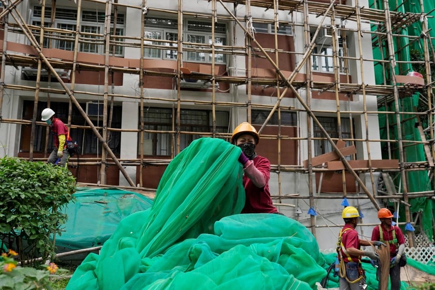 Workers remove scaffolding mesh from a building at Sui Wo Court in Sha Tin, following authorities' decision to remove the netting amid investigations into a deadly fire at Wang Fuk Court, in Hong Kong, China December 4, 2025. REUTERS/Vernon Yuen