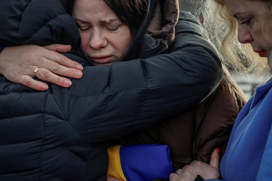 Relatives embrace each other near coffins as they attend the funeral of Ruslan Filipenko, 22, Artur Baranets, 22, and Oleksii Yashchenko, 21, who voluntarily joined local Territorial Defense unit and were killed in March 2, 2022, after they were recently identified by DNA analysis, amid Russia's attack on Ukraine, in the town of Irpin, Kyiv region, Ukraine November 25, 2025. REUTERS/Alina Smutko