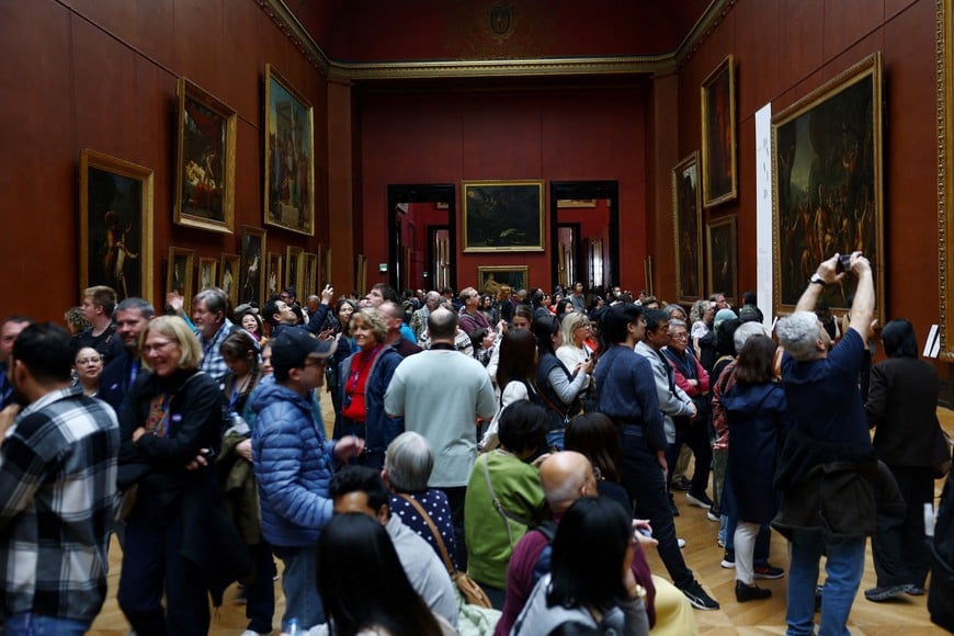 Visitors take pictures of the paintings in the salle Mollien of Denon wing at the Louvre Museum on the day it reopened to the public for the first time since last Sunday's heist, while the Galerie d'Apollon where eight pieces of Napoleon and the Empress's jewelry collection displayed in the gallery were stolen by thieves, remains closed, in Paris, France, October 22, 2025. REUTERS/Gonzalo Fuentes