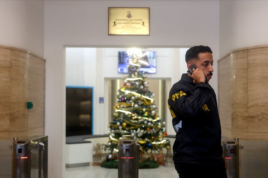 A member of the Argentine Federal Police uses his phone at the entrace of the Argentine Football Association (AFA) headquarters, where Federal Police raid amid investigation into alleged money laundering, according to local media, in Buenos Aires, Argentina December 9, 2025. REUTERS/Cristina Sille