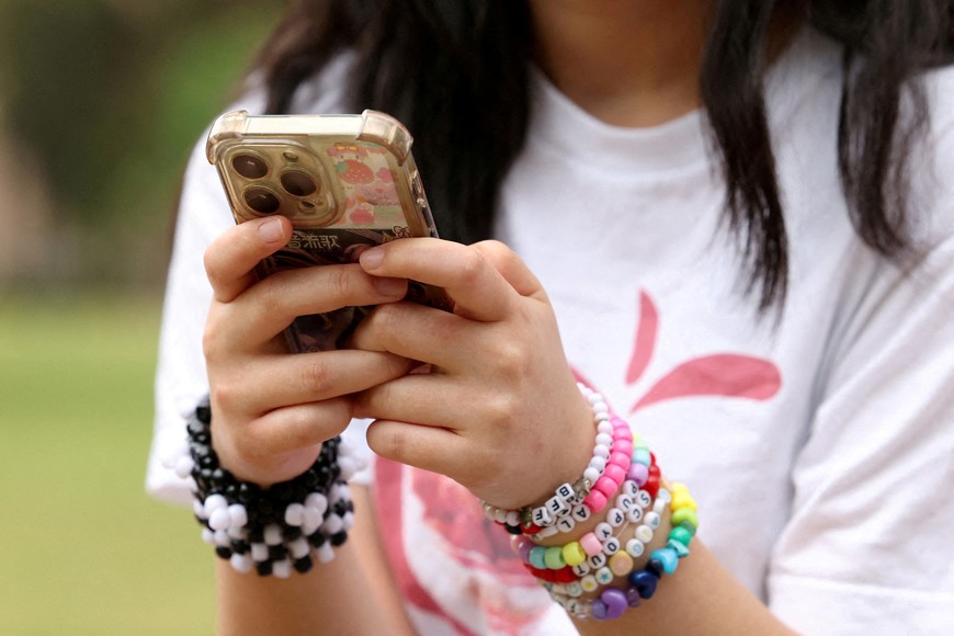 A girl poses holding her phone after an interview discussing Australia's social media ban for users under 16, which is scheduled to take effect on December 10, in Sydney, Australia, November 22, 2025. REUTERS/Hollie Adams