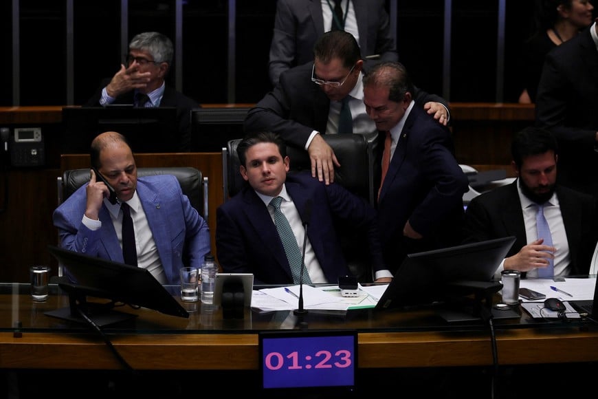 President of the Chamber of Deputies Hugo Motta listens to the federal deputy Sostenes Cavalcante and Paulinho da Forca during a session to vote on a bill, which proposes reducing the sentences for January 8, 2023, riot convictions, including former President Jair Bolsonaro, at the Chamber of Deputies in Brasilia, Brazil, December 10, 2025. REUTERS/Adriano Machado