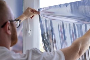Colocación de láminas reflectivas en una ventana para disminuir el impacto del sol directo.