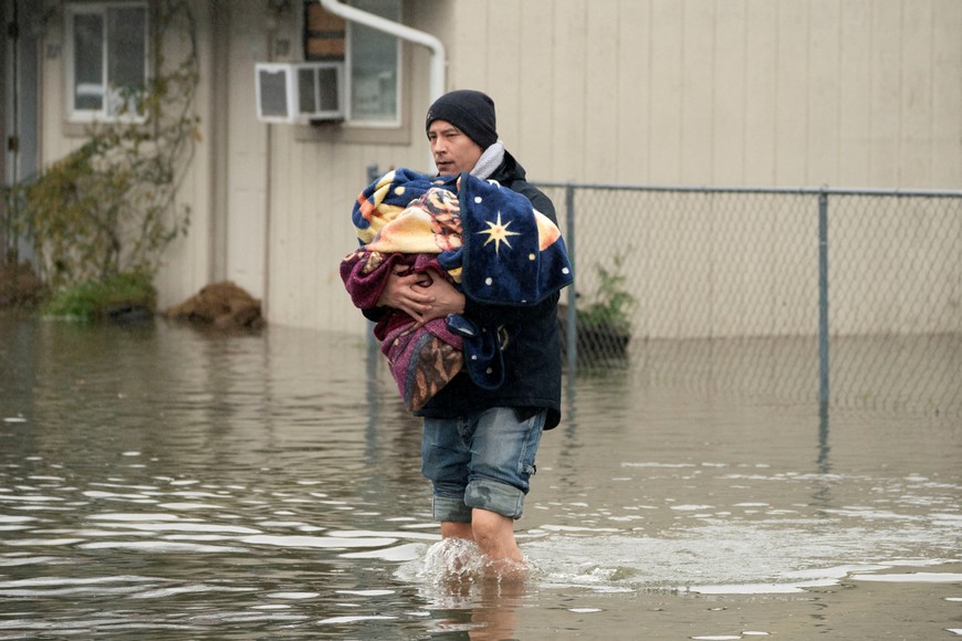 Brandon Phasith carries belongings while evacuating amidst rising floodwater, as an atmospheric river brings rain and flooding to the Pacific Northwest, in Sultan, Washington, U.S., December 10, 2025.  REUTERS/David Ryder