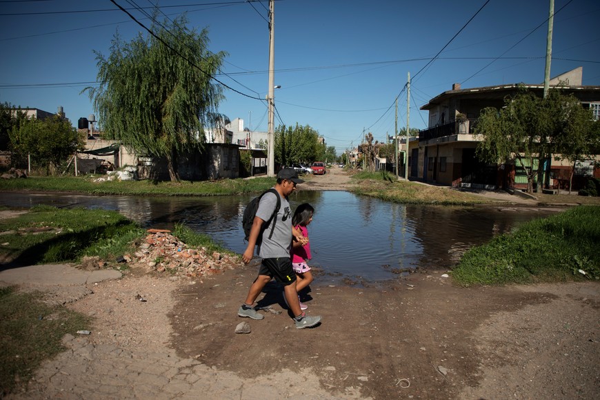 (250403) -- CIUDAD EVITA, 3 abril, 2025 (Xinhua) -- Imagen del 29 de marzo de 2025 de un hombre cruzando una calle inundada junto a su hija, en el Barrio 22 de enero, un asentamiento ubicado en la localidad de Ciudad Evita, Argentina. Los indicadores de pobreza e indigencia en Argentina siguen reflejando una realidad compleja para una gran parte de la población. Aunque los datos oficiales señalan una caída significativa en el segundo semestre de 2024, factores como el reajuste en el sistema de precios, el aumento de los gastos fijos familiares, la contracción del consumo y la reducción de la asistencia comunitaria mantienen vigente una vulnerabilidad social que aún persiste en el país. (Xinhua/Martín Zabala) (mz) (jg) (ah) (vf)