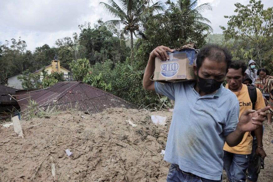 Local residents walk while carrying their belongings in an area hit by deadly landslides following heavy rains in Sibalanga, North Tapanuli, North Sumatra province, Indonesia, November 29, 2025. REUTERS/Agatha Capri